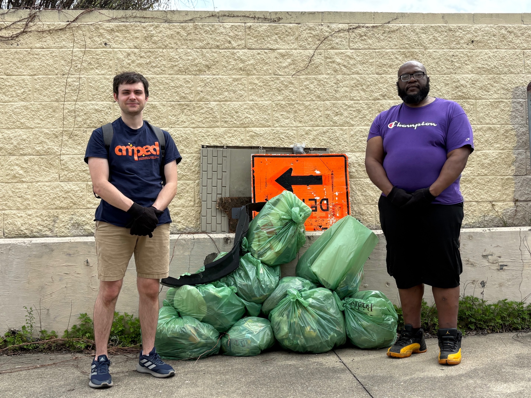 Co-founders Jake Nevitt and Kevan Manning standing on either side of a pile of full green trash bags after the first Scene Cleaning
